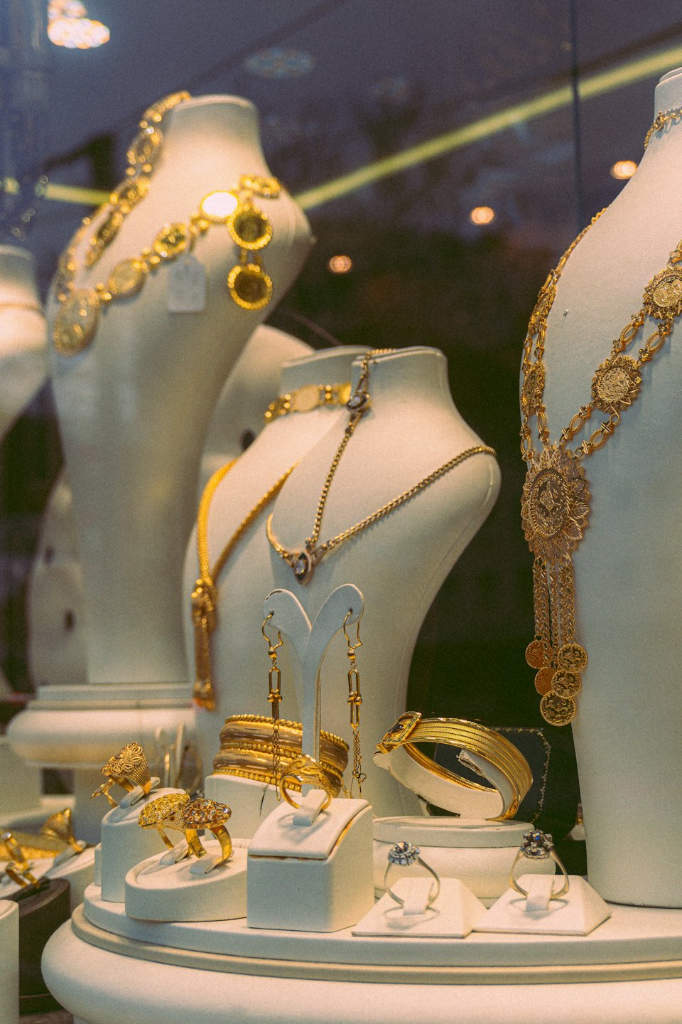 Gold and silver jewelry displayed on stands in a window.